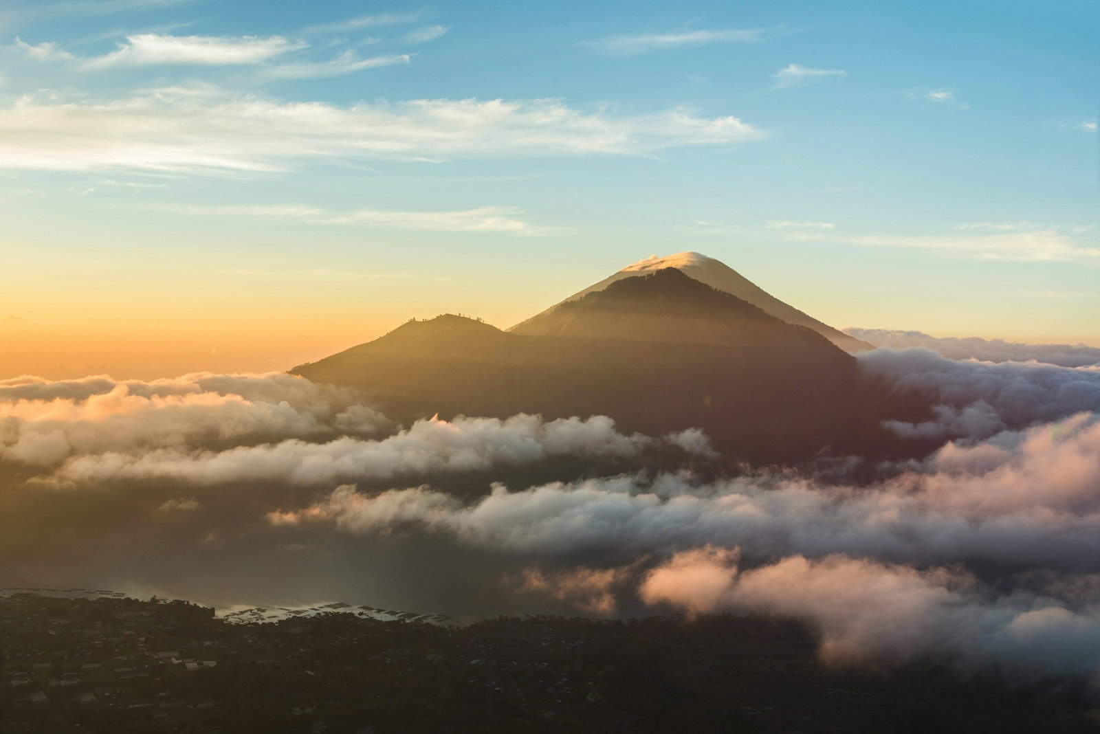 Sunrise over a mountain surrounded by clouds and a town below