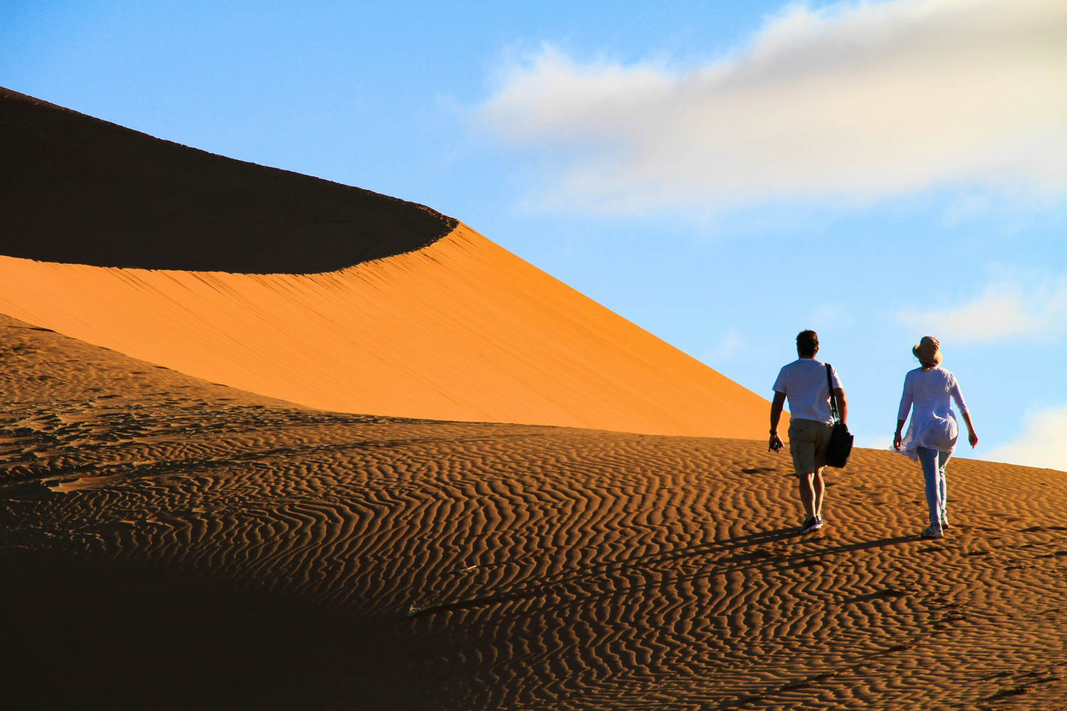 Travellers climbing large sand dunes in Namib desert