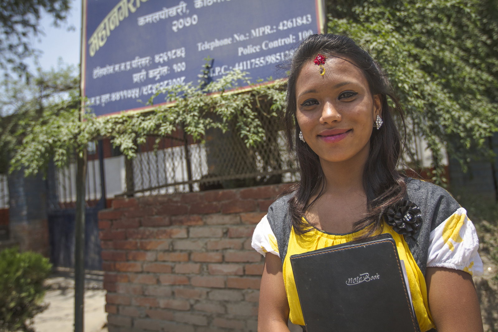 A girl with a notebook standing in front of a building