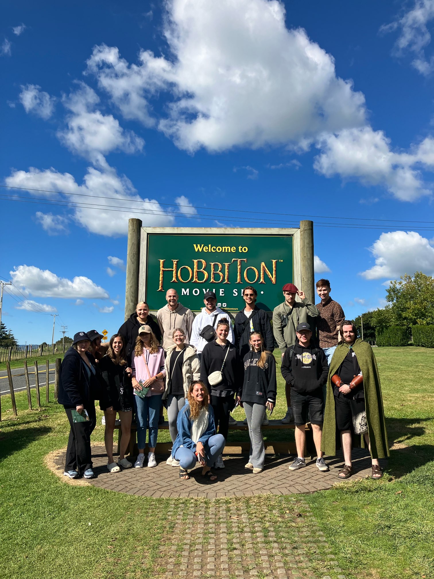 Group of travellers at Hobbiton sign in New Zealand