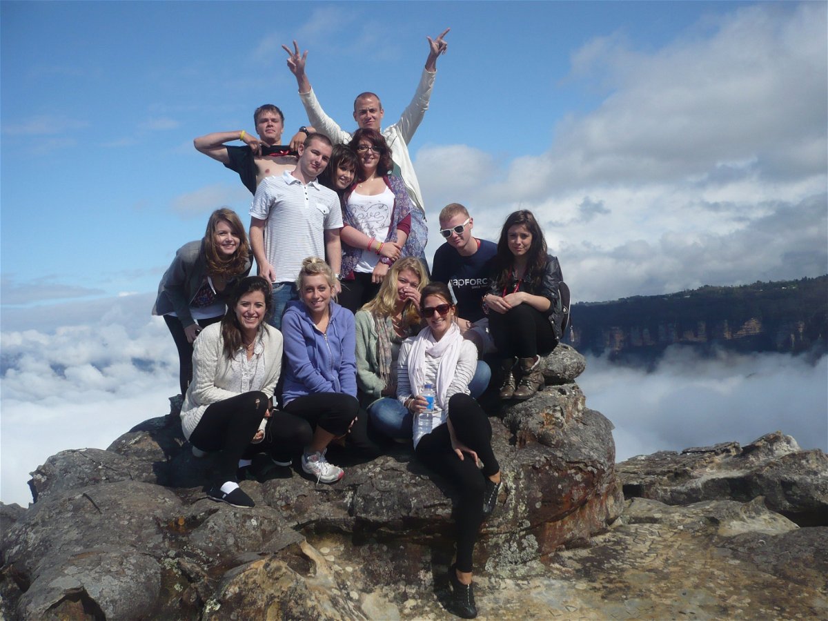 A group of travellers on top of a rock in the Blue Mountains with clouds in the background