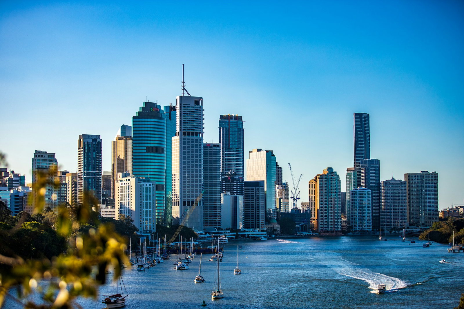 Modern city harbour with bright blue ocean and sailboats riding along, clear blue skies, Australia