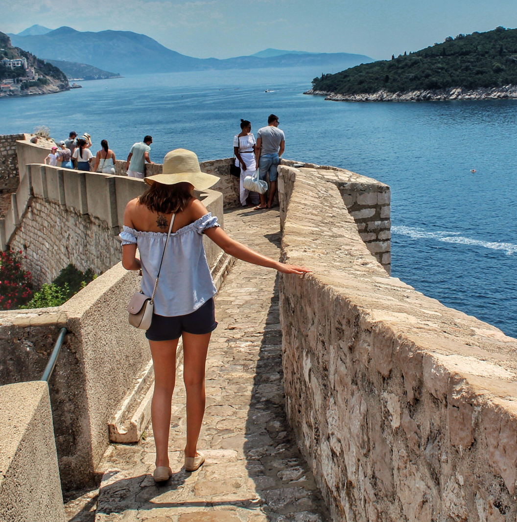 Person standing on wall near Croatia coastline 
