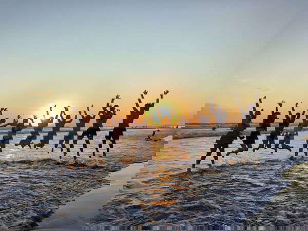 Travellers jumping on balinese beach with sunset behind them