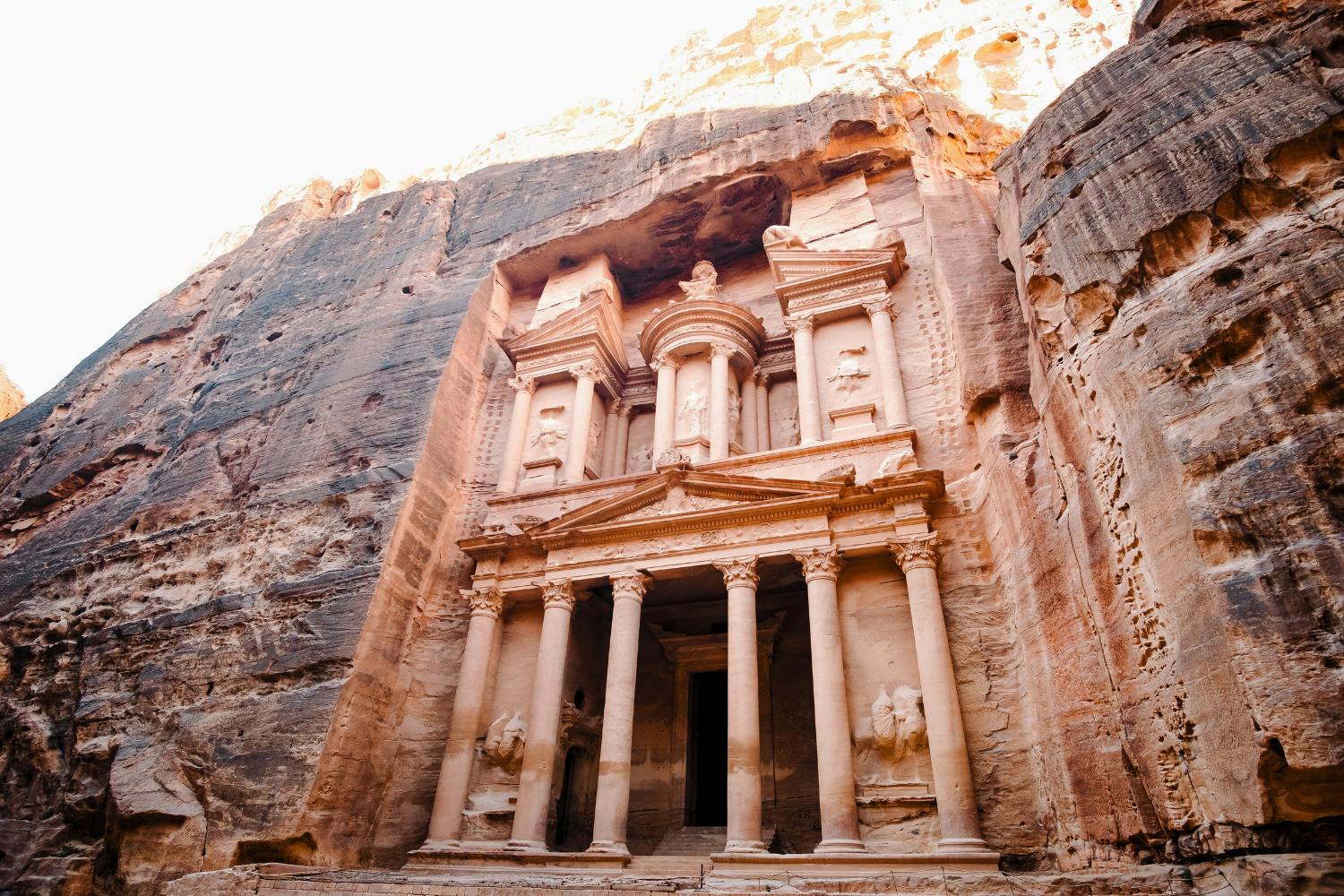 The Treasury in Petra and surrounding sandstone cliffs in Jordan