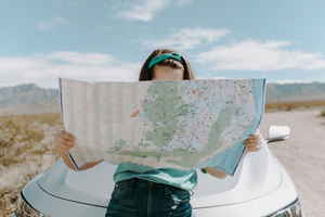 Person reading a map in front of a car
