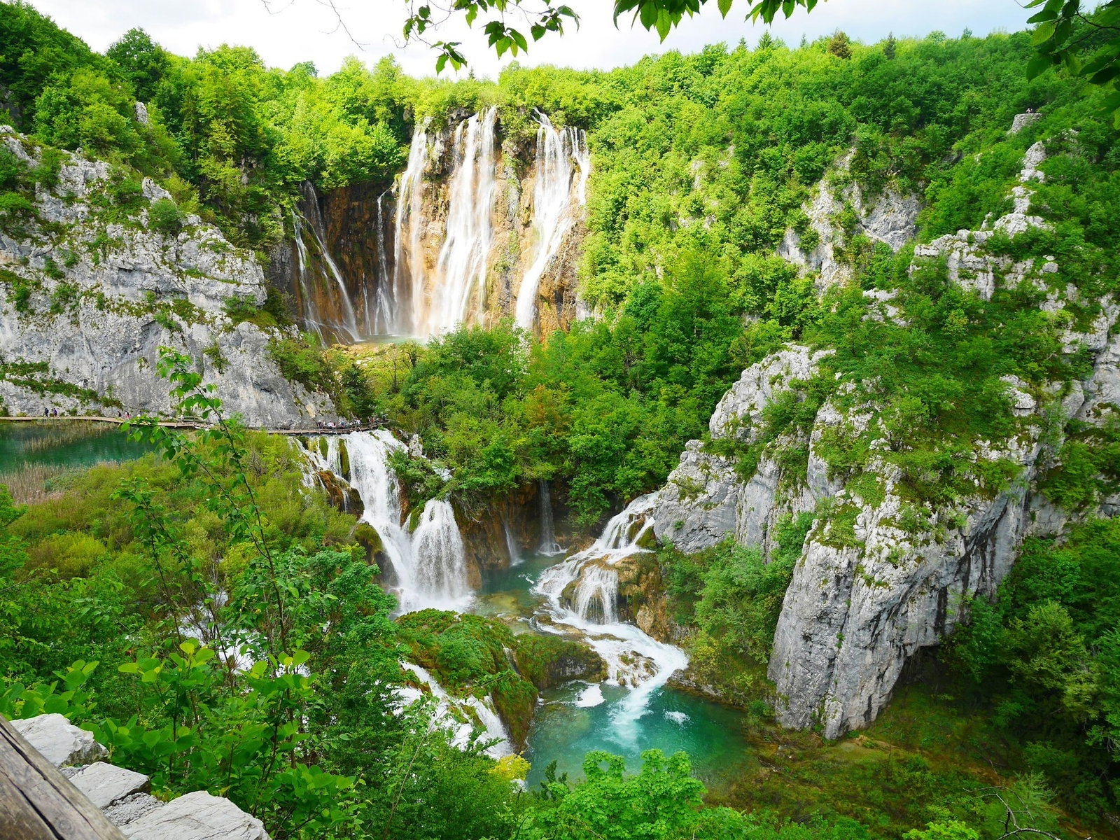 Waterfall viewpoint of cascading rivers surrounded by grey rocks and emerald forest