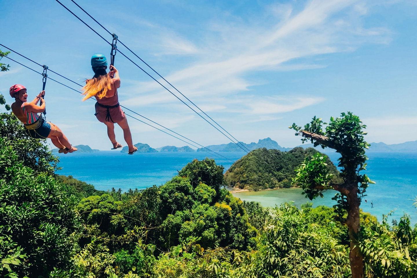 two girls zip-lining over jungle