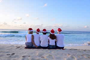 Backpackers sat on beach with christmas hats on