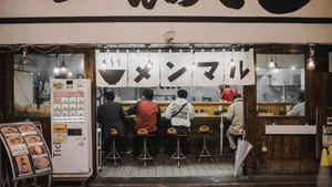 Four people sitting on stools at a restaurant in Japan