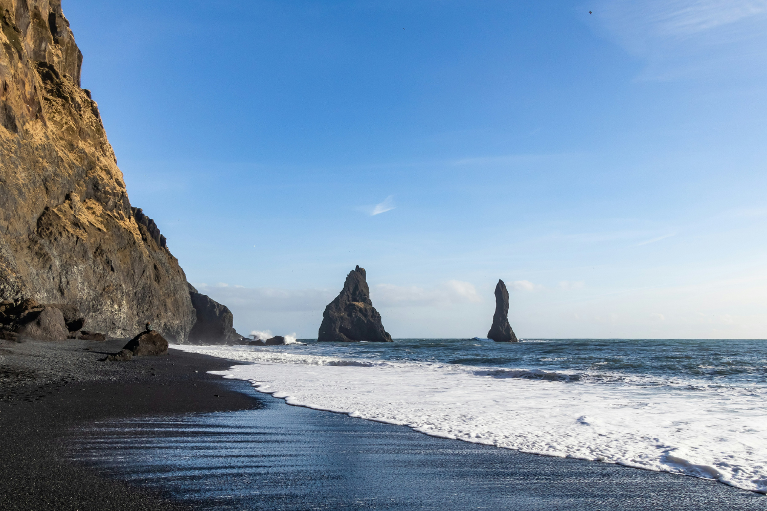 Iceland's black sand beach, Reynisfjara, and Reynisdrangar sea stacks rising out of the ocean