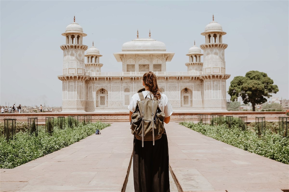 Woman with a backpack standing in front of a temple in India