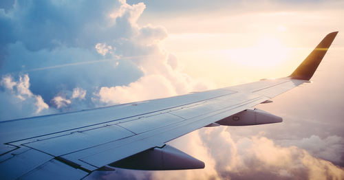 Wing view of sun and clouds from airplane