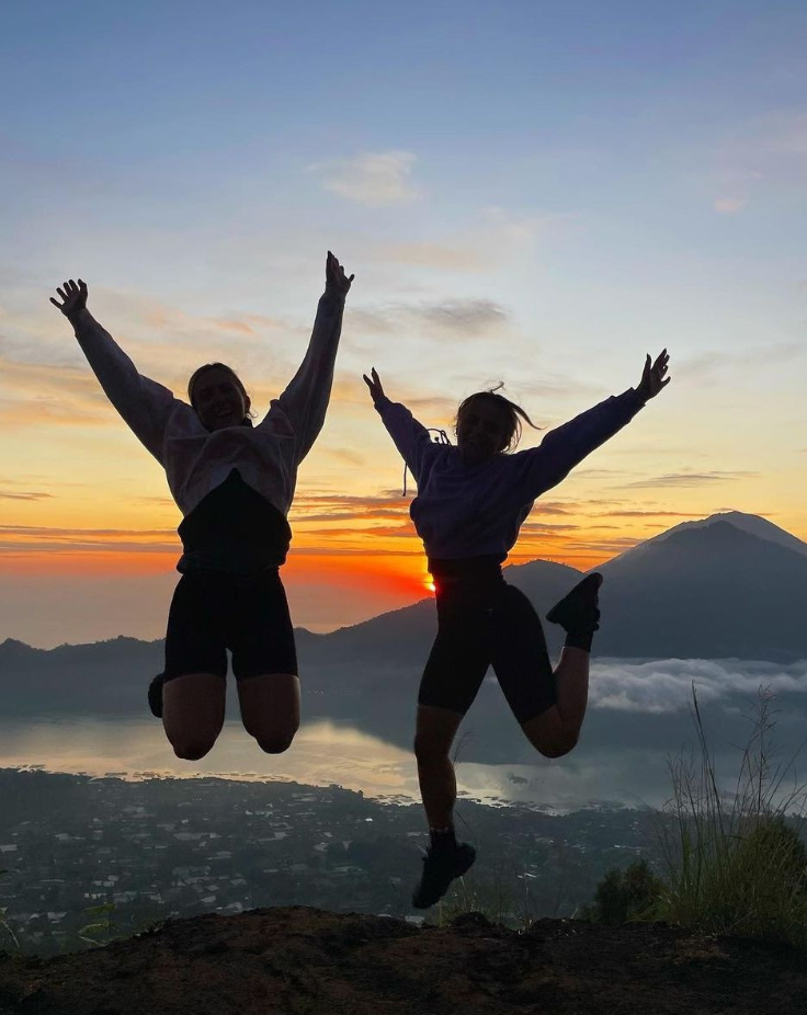 Travellers jumping in air with Mount Batur sunrise behind them