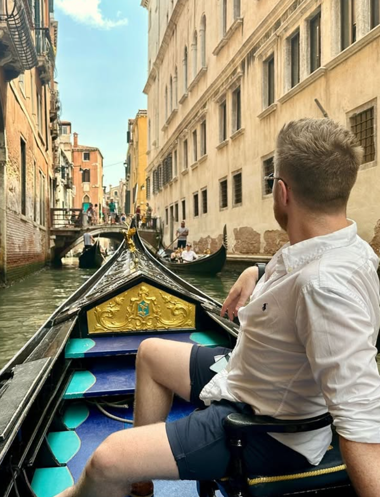 Traveller sat on gondola down canal in Venice