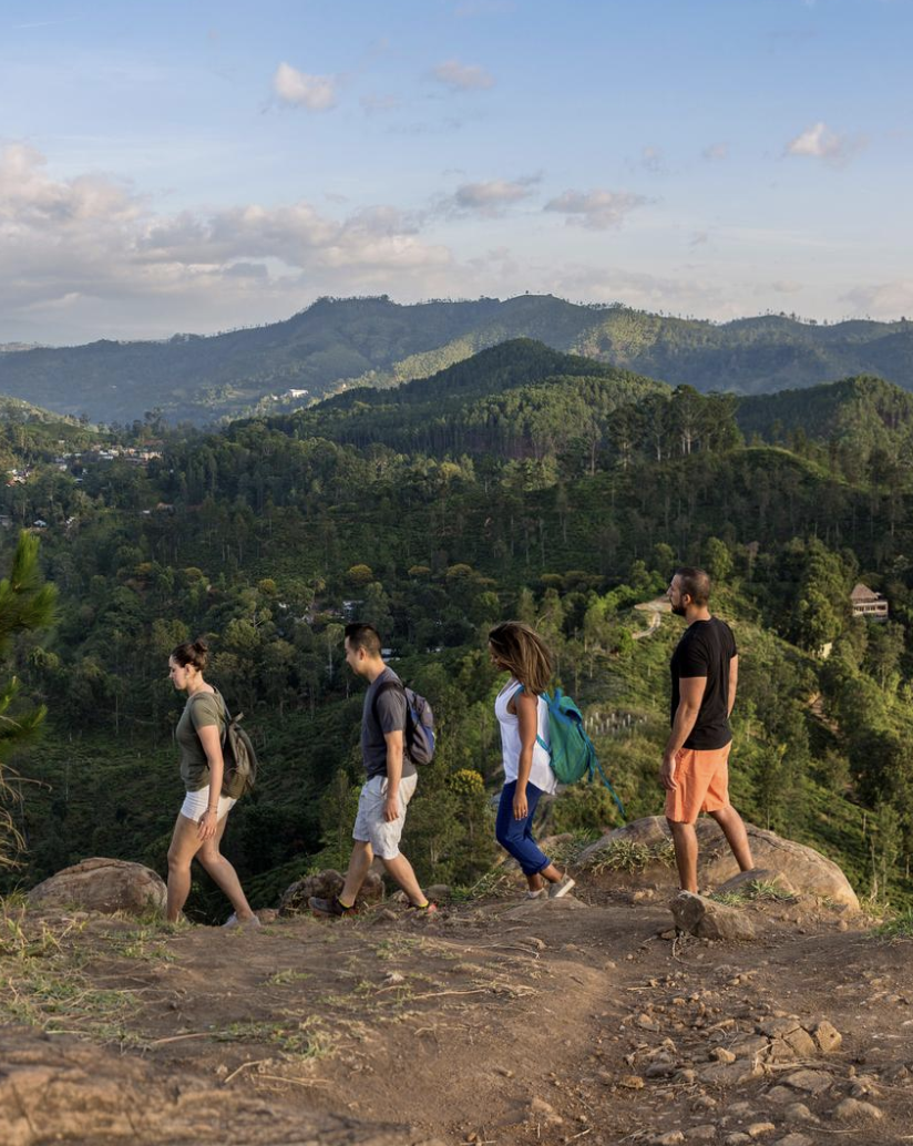 Travellers walking at Little Adams Peak at sunrise in Ella