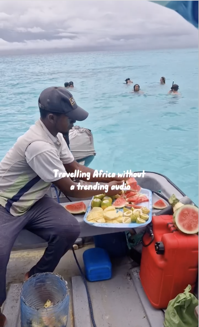 Local guide preparing fruit for travellers on a group trip in Tanzania as they snorkel off Zanzibar island