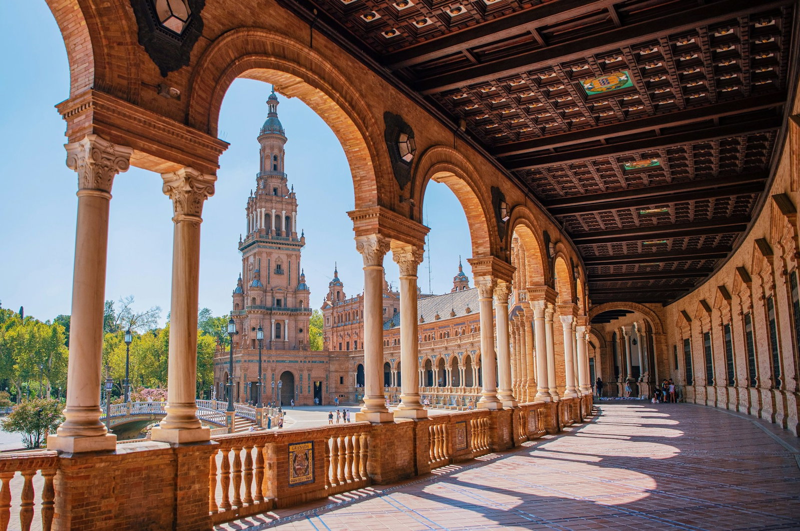 Traditional archways leading around stunning golden buildings in Seville's main square