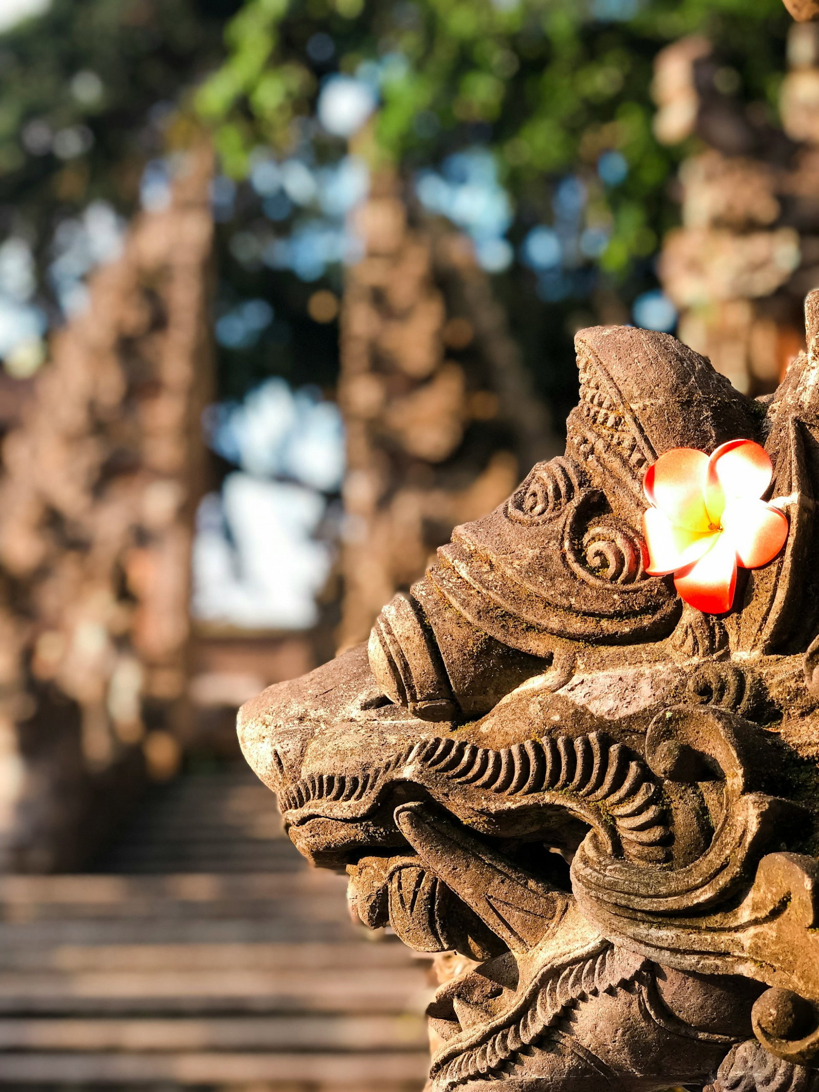 Traditional animal statue with a flower and gates in the distance, Ubud