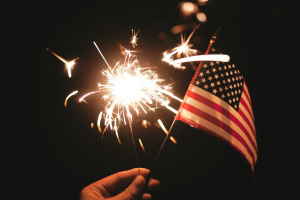 A hand holding a sparkler and American flag