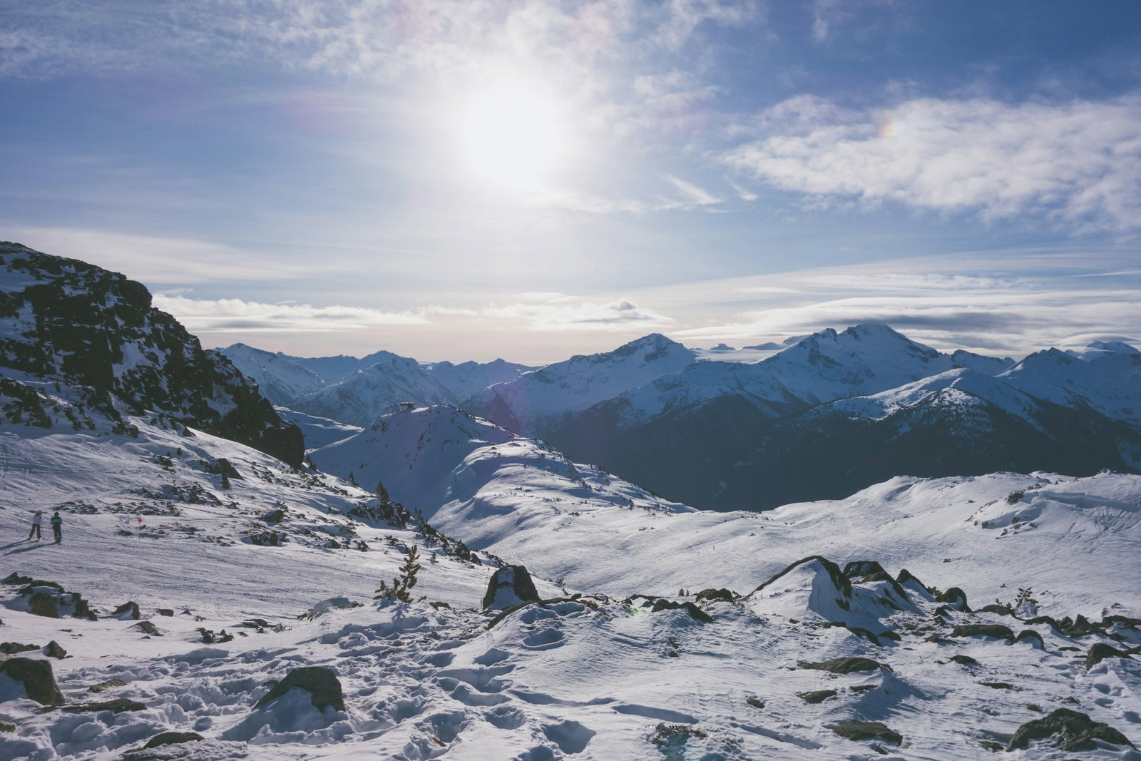 Sunny winter morning in mountains covered with snow and two people outside dressed for skiing