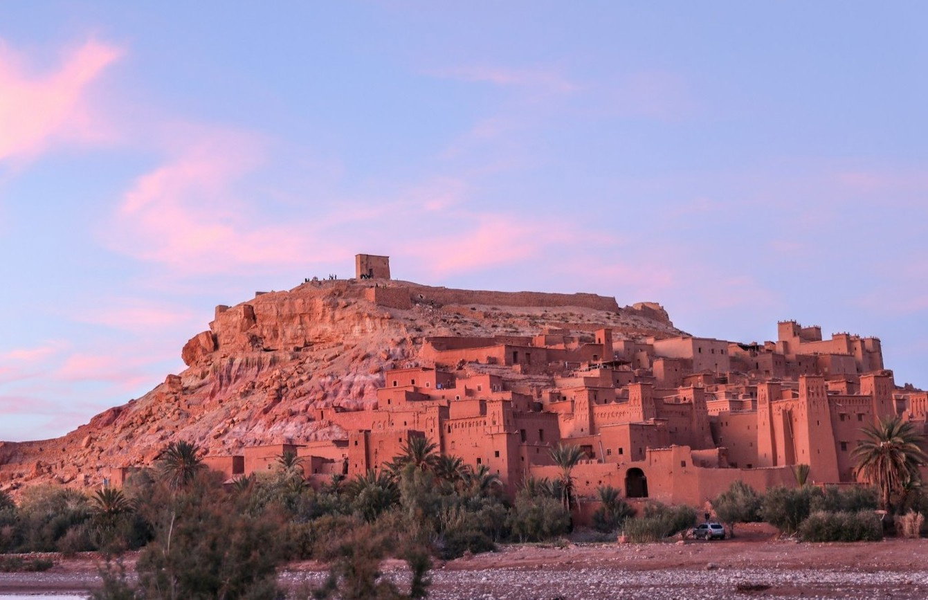 Orange clay buildings carved into rugged cliffs at sunset