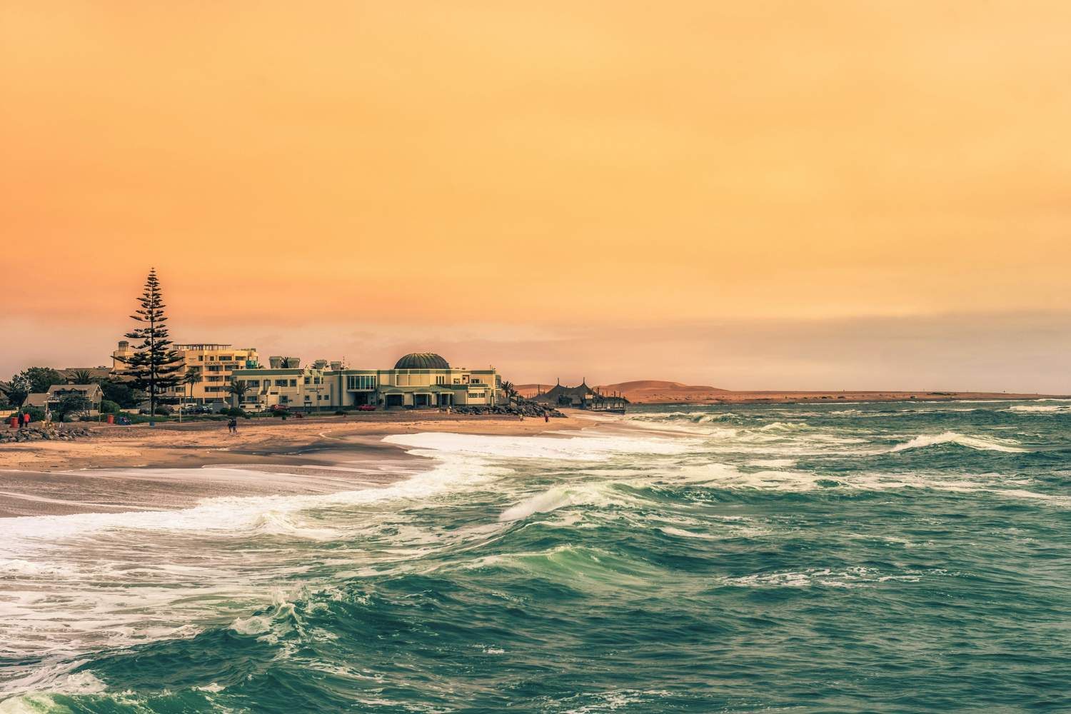 Sunset across the coast on Swakopmund city and waves crashing onto the beach