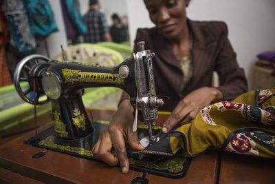 African woman sewing colourful clothes with sewing machine