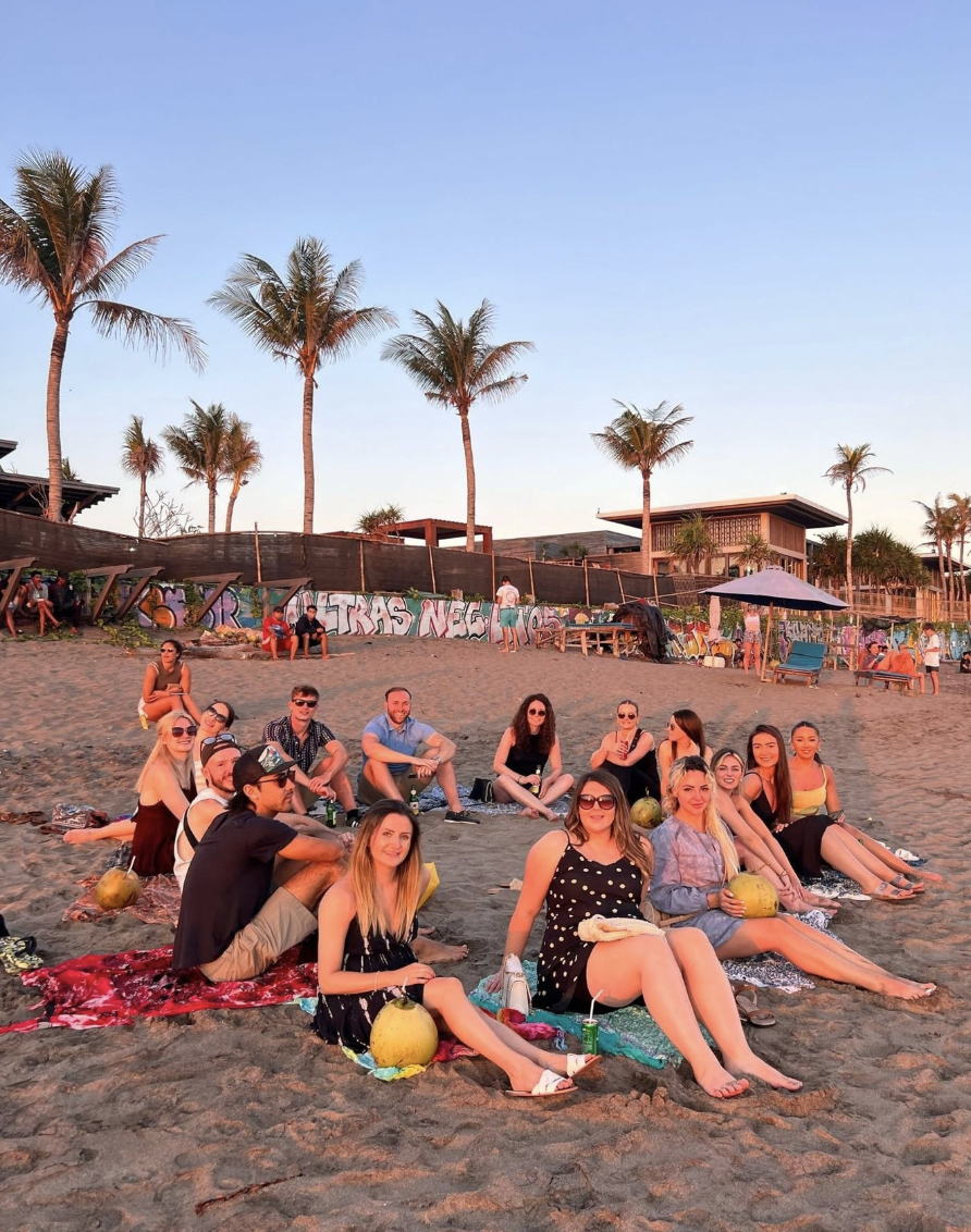 Travellers drinking fresh coconuts on the beach at sunset in Bali