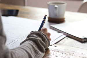 A persons sits at a table writing notes