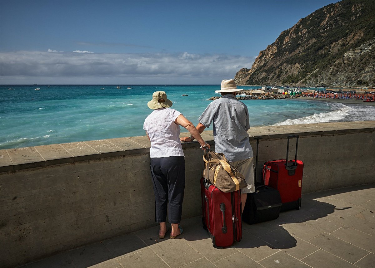 An older couple with luggage, overlooking the sea