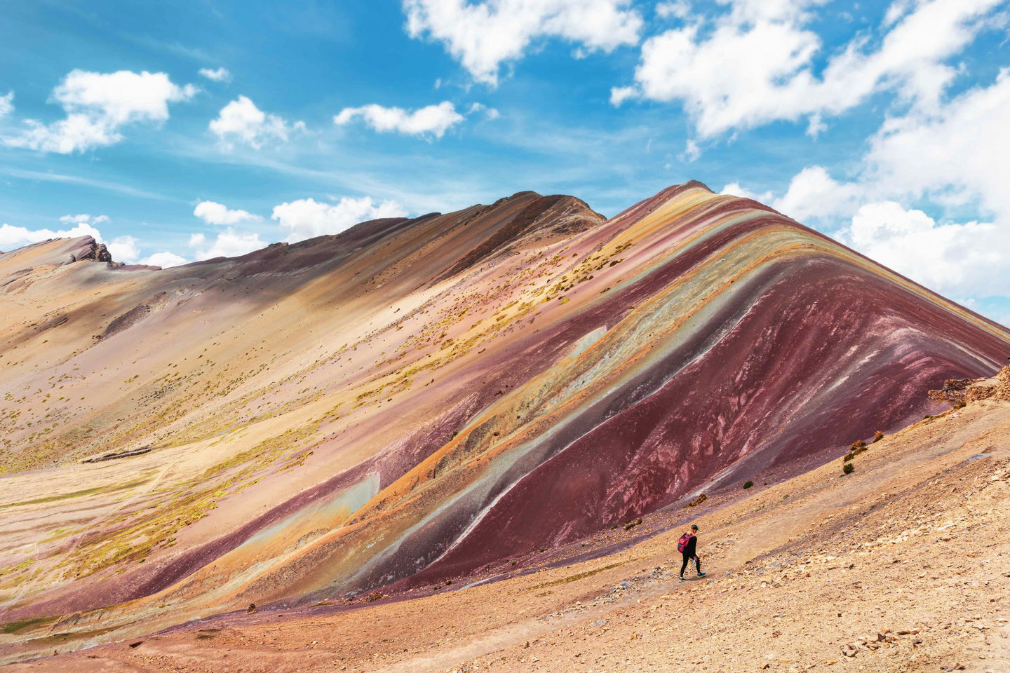 Hiker walking in front of view of the Rainbow Mountains