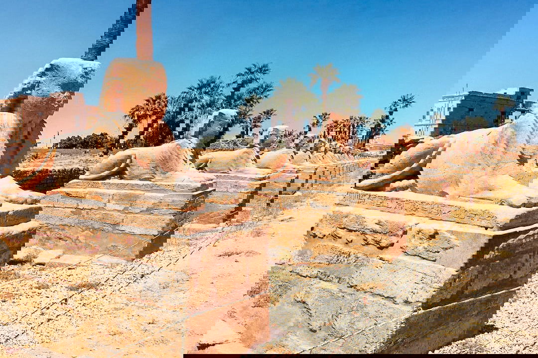 Stone structure of sphinx with palm tree and blue sky