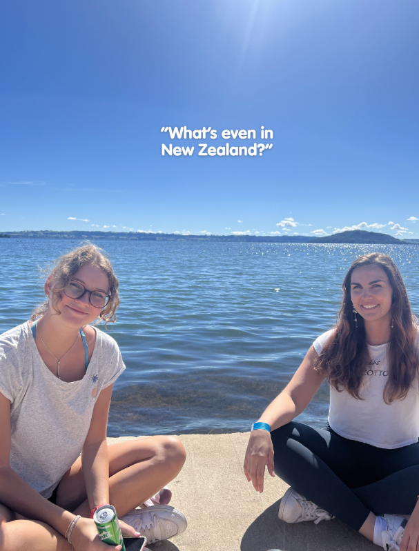 What's even in New Zealand with travellers sat in front of lake with sunny blue skies