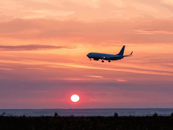 Plane flying over sunset sky