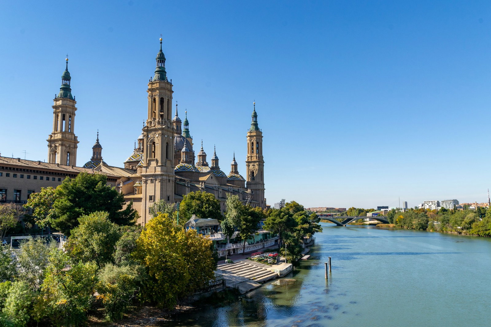 Traditional building and waterfront in Zaragoza with bridge connecting to modern city